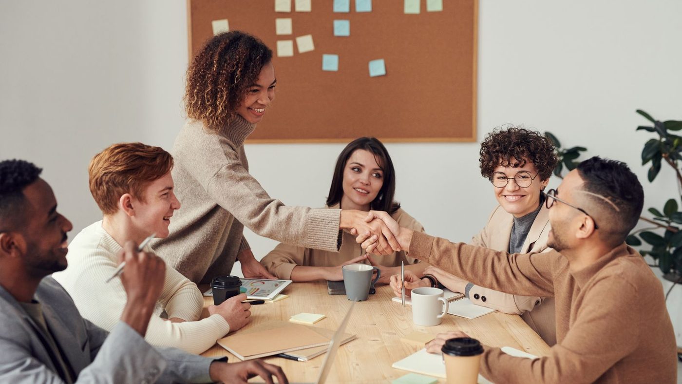 Equipo diverso de profesionales cerrando un acuerdo con un apretón de manos en una reunión